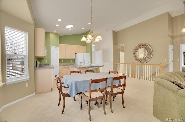 dining space with baseboards, light colored carpet, an inviting chandelier, high vaulted ceiling, and recessed lighting