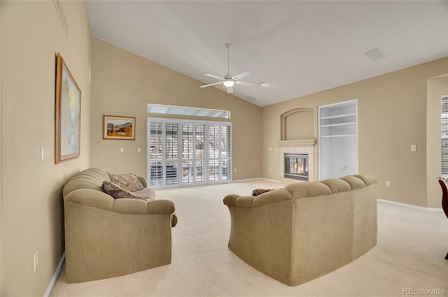 living area featuring light carpet, ceiling fan, baseboards, and a tiled fireplace