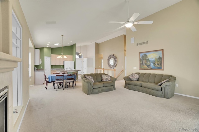 living room featuring high vaulted ceiling, light carpet, visible vents, baseboards, and a tiled fireplace