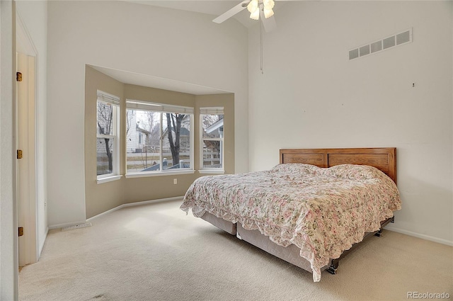 carpeted bedroom featuring baseboards, a high ceiling, visible vents, and a ceiling fan