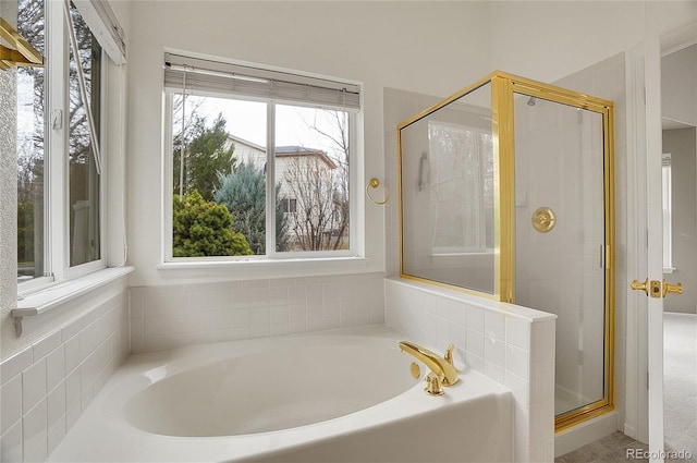 full bath featuring a healthy amount of sunlight, a garden tub, and a shower stall