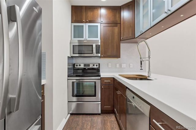 kitchen with sink, appliances with stainless steel finishes, dark hardwood / wood-style flooring, and backsplash