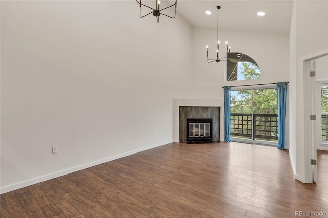 unfurnished living room featuring high vaulted ceiling, a chandelier, and dark hardwood / wood-style flooring