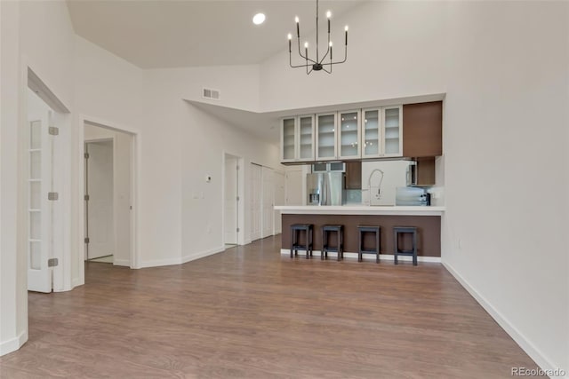 unfurnished living room with an inviting chandelier, hardwood / wood-style floors, and high vaulted ceiling