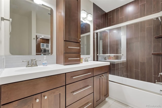 bathroom featuring backsplash, dual vanity, tile patterned floors, and shower / bath combination with glass door