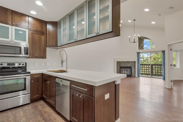 kitchen with hardwood / wood-style flooring, stainless steel appliances, hanging light fixtures, sink, and an inviting chandelier