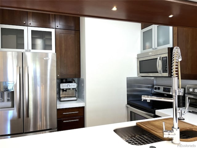 1000 E 1st Ave Unit 405, Denver, CO 80218 - kitchen with light countertops, dark brown cabinets, appliances with stainless steel finishes, and decorative backsplash