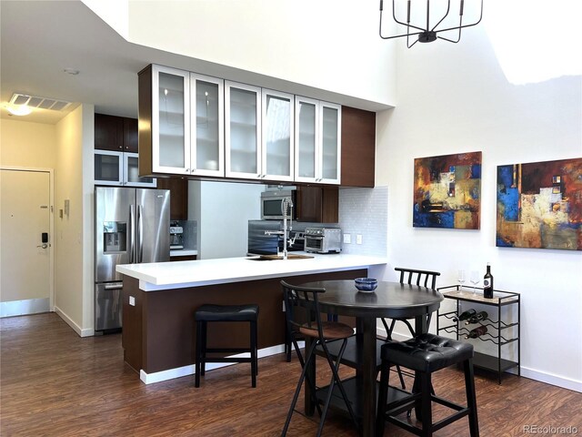 1000 E 1st Ave Unit 405, Denver, CO 80218 - kitchen featuring dark brown cabinetry, dark wood-style flooring, light countertops, a peninsula, and stainless steel appliances