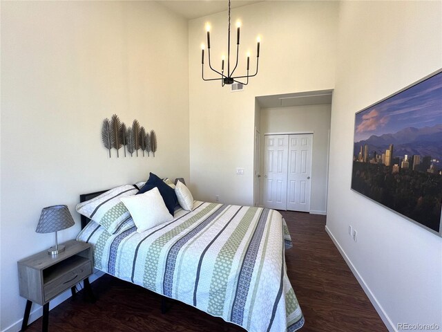 1000 E 1st Ave Unit 405, Denver, CO 80218 - bedroom featuring an inviting chandelier, a closet, a towering ceiling, wood finished floors, and baseboards