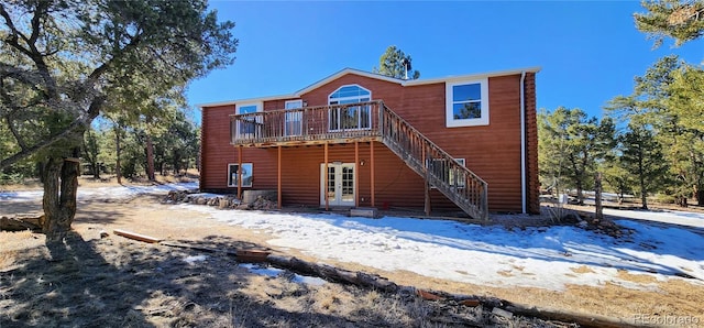 snow covered back of property with a deck