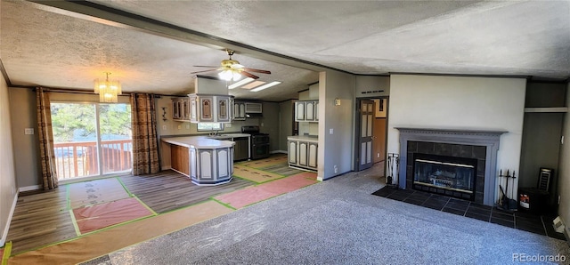 kitchen with a tile fireplace, vaulted ceiling with beams, sink, double oven range, and a textured ceiling