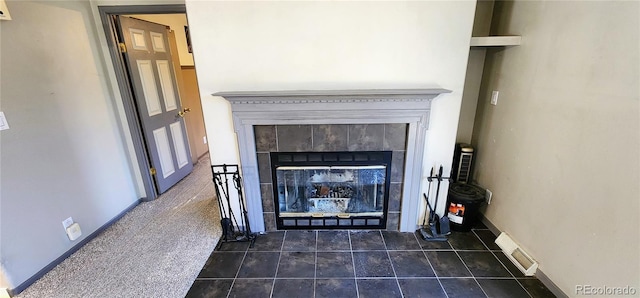 interior details featuring a tiled fireplace and carpet