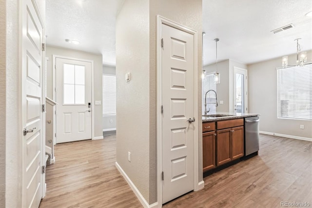 kitchen featuring light hardwood / wood-style flooring, dishwasher, sink, and hanging light fixtures