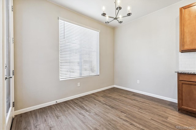 unfurnished dining area with hardwood / wood-style floors and an inviting chandelier