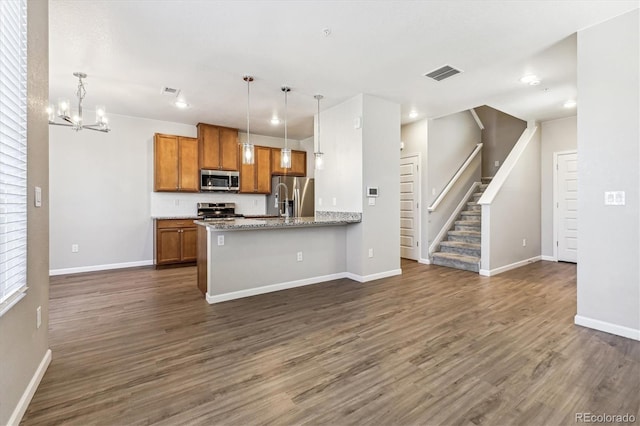 kitchen featuring dark hardwood / wood-style flooring, a chandelier, stainless steel appliances, pendant lighting, and light stone counters