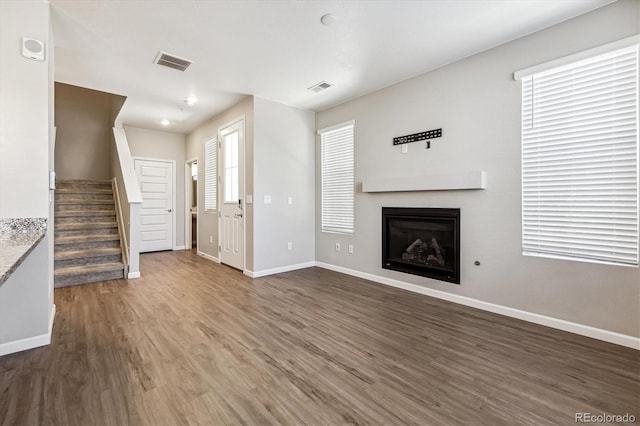 unfurnished living room with plenty of natural light and dark hardwood / wood-style flooring