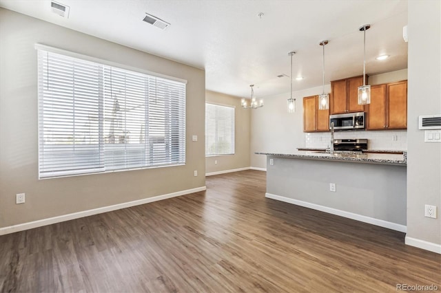 kitchen featuring light stone countertops, stainless steel appliances, backsplash, and dark hardwood / wood-style flooring