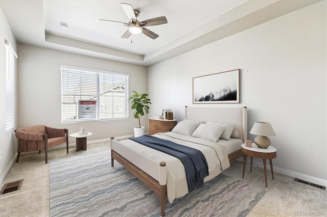 carpeted bedroom featuring ceiling fan and a tray ceiling