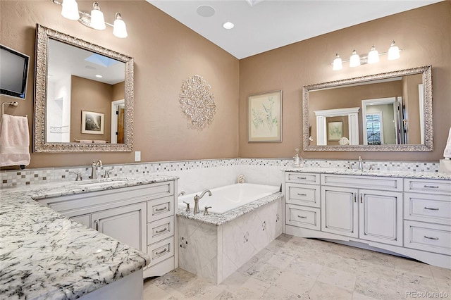 bathroom featuring tiled bath and vanity