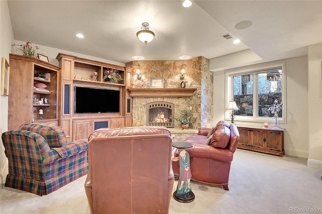 carpeted living room with a stone fireplace