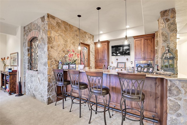 bar featuring light carpet, light stone countertops, and decorative light fixtures