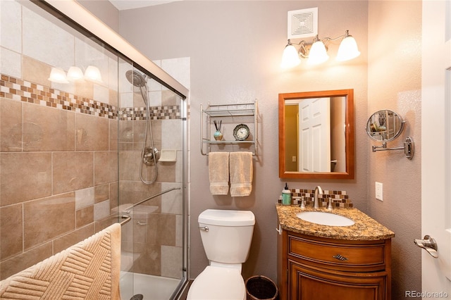 bathroom featuring vanity, toilet, and a shower with shower door