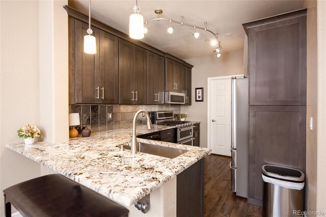 kitchen with pendant lighting, sink, a kitchen bar, kitchen peninsula, and stainless steel appliances