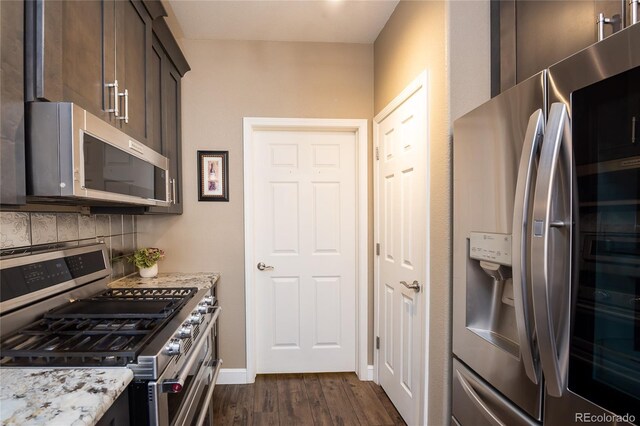 kitchen with dark hardwood / wood-style floors, tasteful backsplash, dark brown cabinetry, stainless steel appliances, and light stone countertops