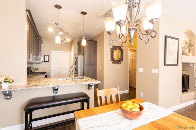 dining area with dark wood-type flooring, a chandelier, and sink