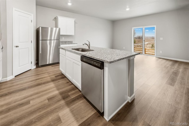 2175 Alyssa St, Fort Lupton, CO 80621 - kitchen with appliances with stainless steel finishes, a sink, a kitchen island with sink, light stone countertops, and white cabinetry