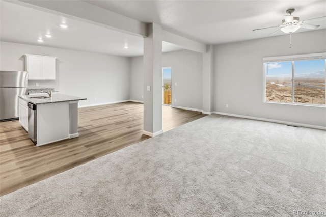 2175 Alyssa St, Fort Lupton, CO 80621 - unfurnished living room with a sink, ceiling fan, light colored carpet, baseboards, and light wood-style floors