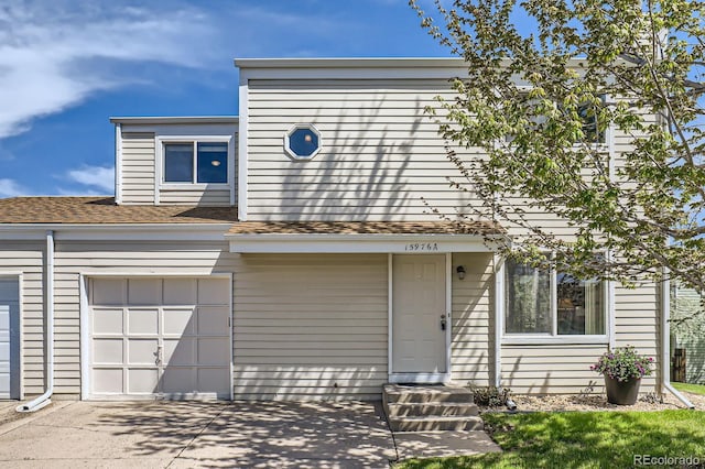 townhome / multi-family property with driveway, roof with shingles, and an attached garage