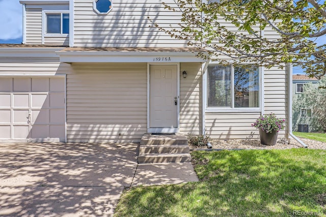 entrance to property with an attached garage and a lawn