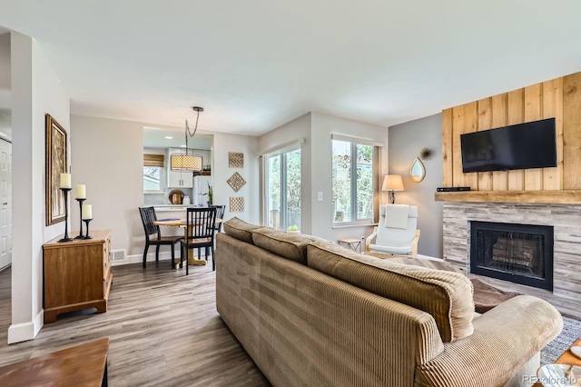 living room featuring a stone fireplace, wood finished floors, and baseboards
