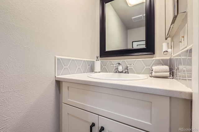 bathroom with tasteful backsplash, vanity, and a textured wall