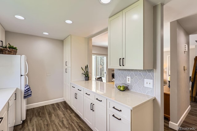 kitchen with freestanding refrigerator, dark wood finished floors, baseboards, tasteful backsplash, and light countertops