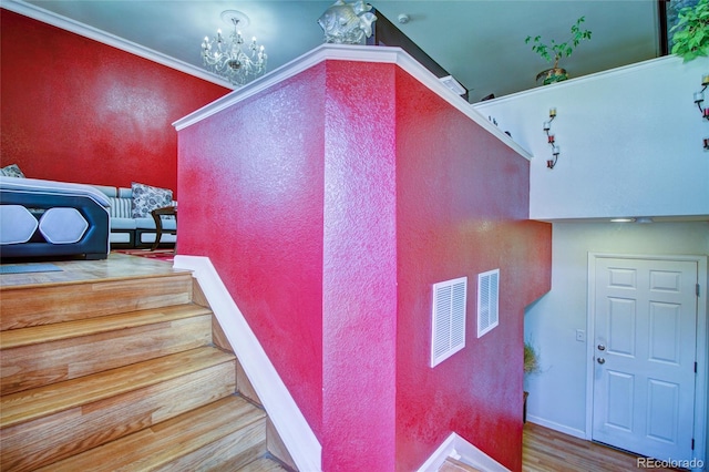 stairway featuring a chandelier, a textured wall, baseboards, and wood finished floors