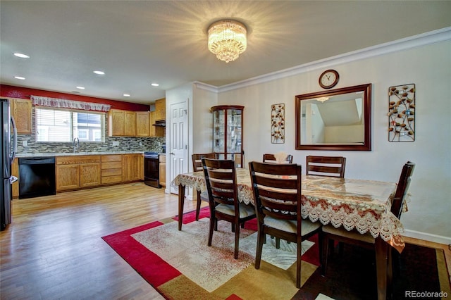 dining space with light wood-type flooring, crown molding, recessed lighting, and an inviting chandelier