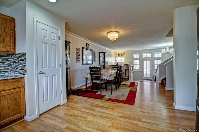 dining area with light wood-style flooring, baseboards, stairway, an inviting chandelier, and crown molding