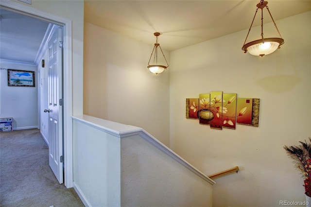 corridor with carpet floors, baseboards, and an upstairs landing