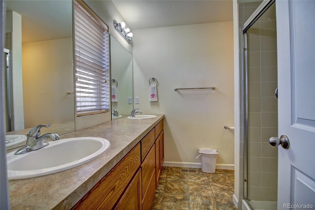 bathroom featuring a tile shower, double vanity, a sink, and visible vents