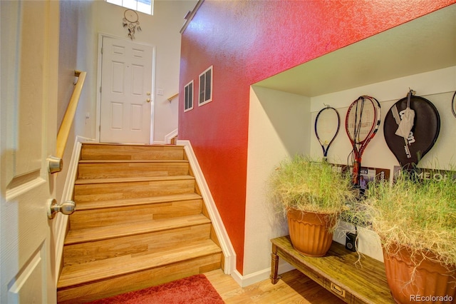 stairway with wood finished floors, visible vents, and baseboards