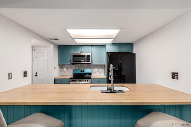 401 S Kalispell Way Unit 104, Aurora, CO 80017 - kitchen featuring stainless steel appliances, wooden counters, a kitchen bar, and decorative backsplash