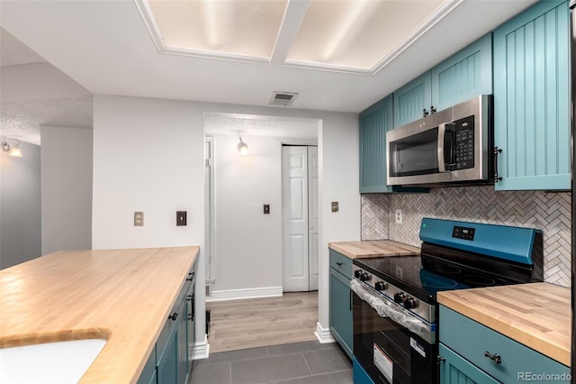 401 S Kalispell Way Unit 104, Aurora, CO 80017 - kitchen featuring butcher block countertops, appliances with stainless steel finishes, dark tile patterned floors, and backsplash