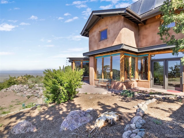 551 Panorama Way, Crestone, CO 81131 - rear view of property featuring stucco siding, a sunroom, a patio, a metal roof, and french doors