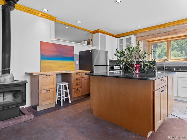 551 Panorama Way, Crestone, CO 81131 - kitchen with a wood stove, freestanding refrigerator, a center island, white cabinetry, and recessed lighting