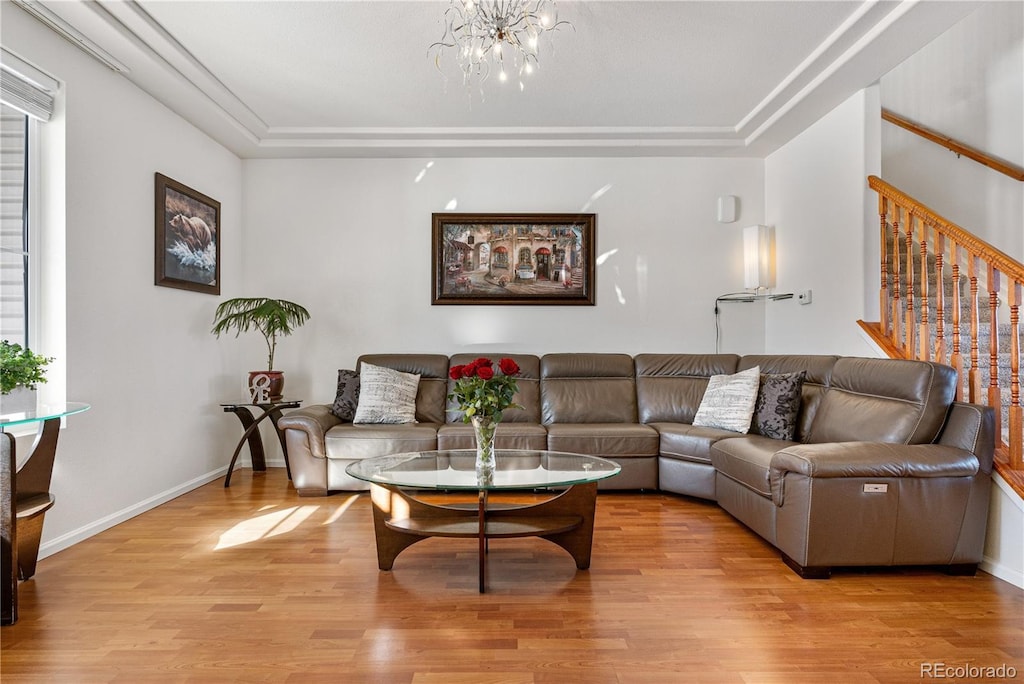 living room featuring a tray ceiling, a chandelier, and light hardwood / wood-style floors