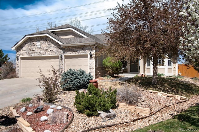 view of front facade with concrete driveway, a shingled roof, an attached garage, and stone siding
