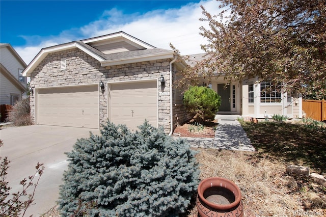 view of front of house featuring driveway, an attached garage, and stone siding