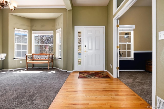 foyer entrance with baseboards, carpet flooring, and wood finished floors
